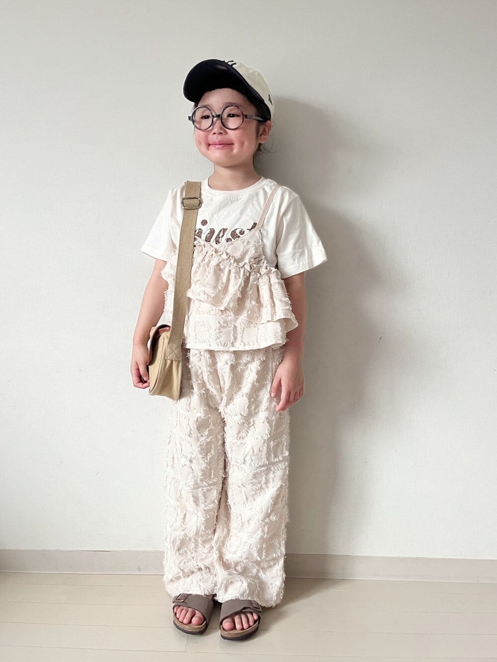 ベージュ系のショルダーバッグ、ブラウン系のサンダル、ベージュ系のTシャツ/カットソーを着用したキッズの春コーディネートの2枚目の写真