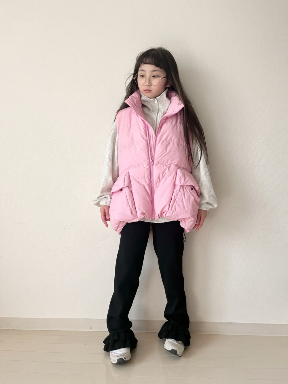 ブラック系のその他パンツ、ピンク系のダウンベスト、ベージュ系のスウェットを着用したキッズの冬コーディネートの2枚目の写真