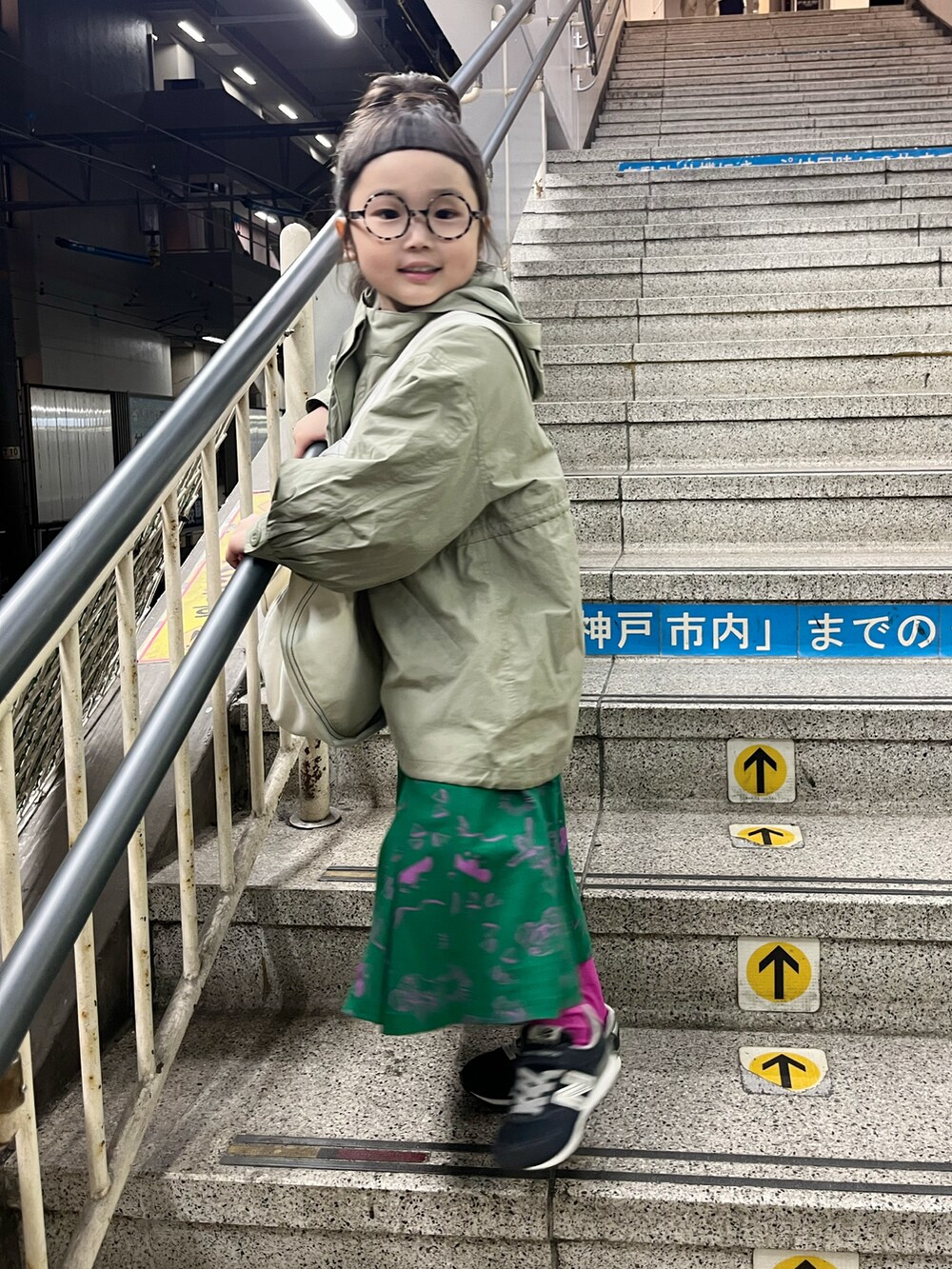 グリーン系のワンピース、ホワイト系のショルダーバッグ、グリーン系のステンカラーコートを着用したキッズの春コーディネートの4枚目の写真