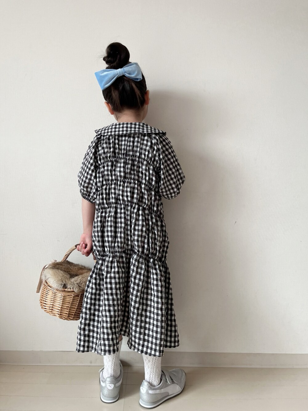 ブラック系のワンピース、ブラック系のカーディガン/ボレロ、ホワイト系のスニーカーを着用したキッズの冬コーディネートの5枚目の写真