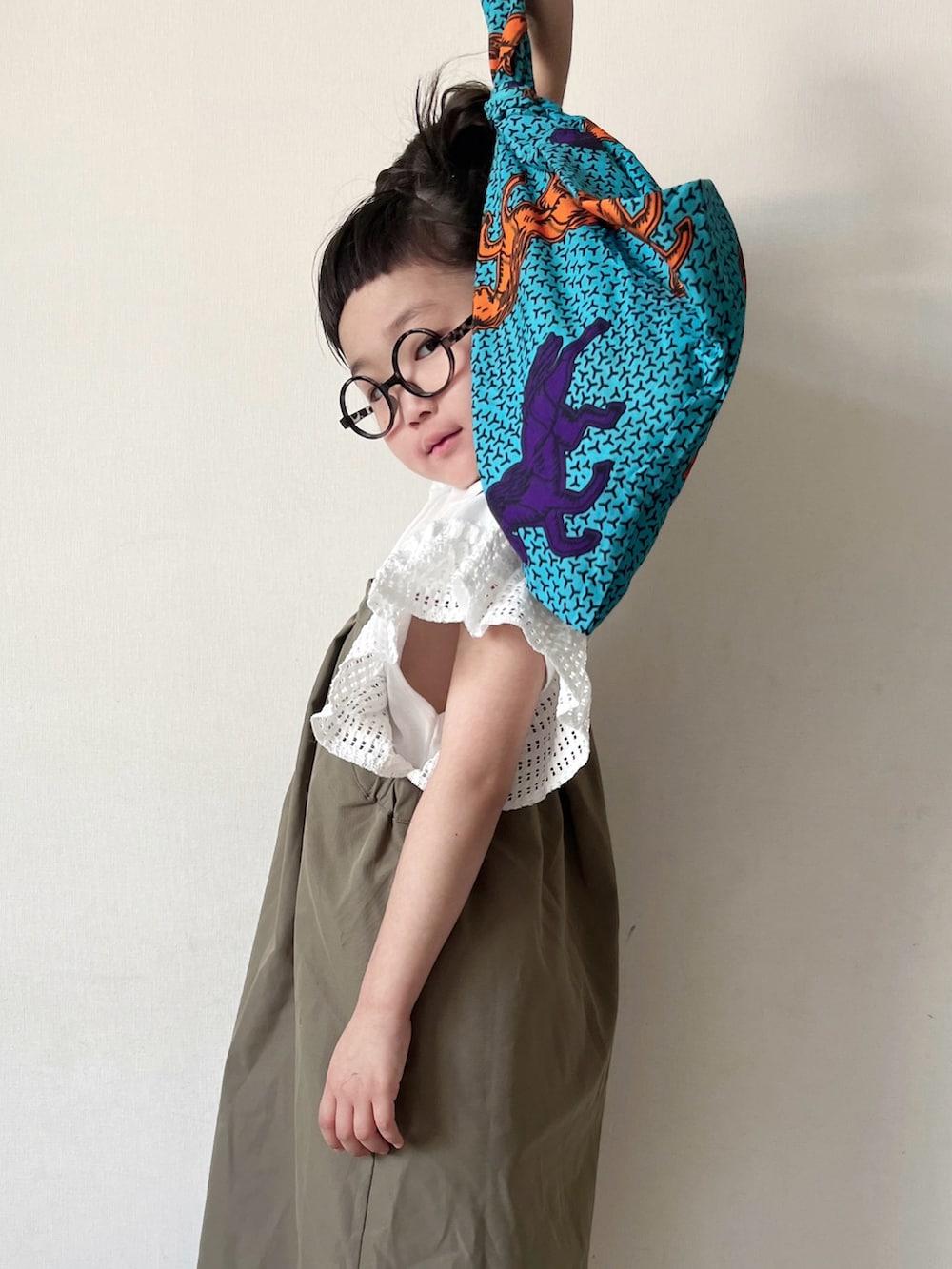 グリーン系のワンピース、ブルー系のハンドバッグ、グリーン系のサンダルを着用したキッズの夏コーディネートの3枚目の写真