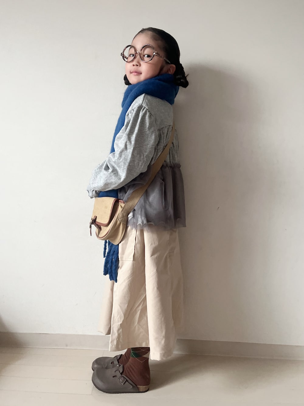 グレー系のカーディガン/ボレロ、ベージュ系のショルダーバッグ、ベージュ系のスカートを着用したキッズの秋コーディネートの3枚目の写真