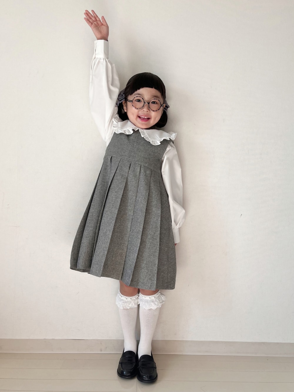 グレー系のジャンパースカート、ホワイト系のシャツ/ブラウス、ブラック系のローファーを着用したキッズの冬コーディネートの3枚目の写真