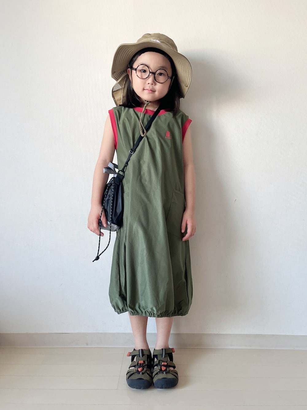 グリーン系のワンピース、ブラック系のショルダーバッグ、グリーン系のサンダルを着用したキッズの夏コーディネートの2枚目の写真