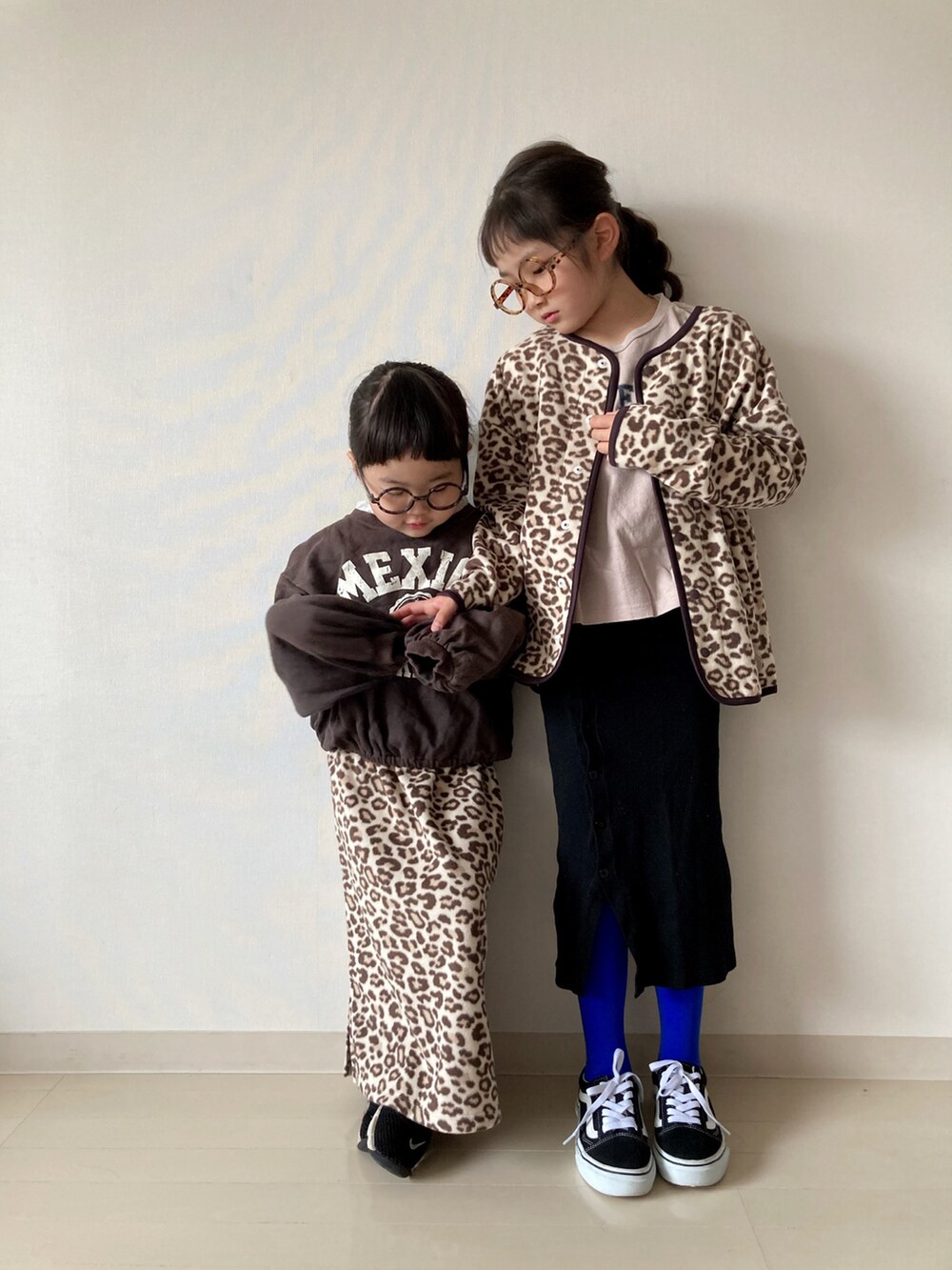 ベージュ系のカーディガン/ボレロ、ベージュ系のTシャツ/カットソー、ブラック系のスニーカーを着用したキッズの冬コーディネートの3枚目の写真