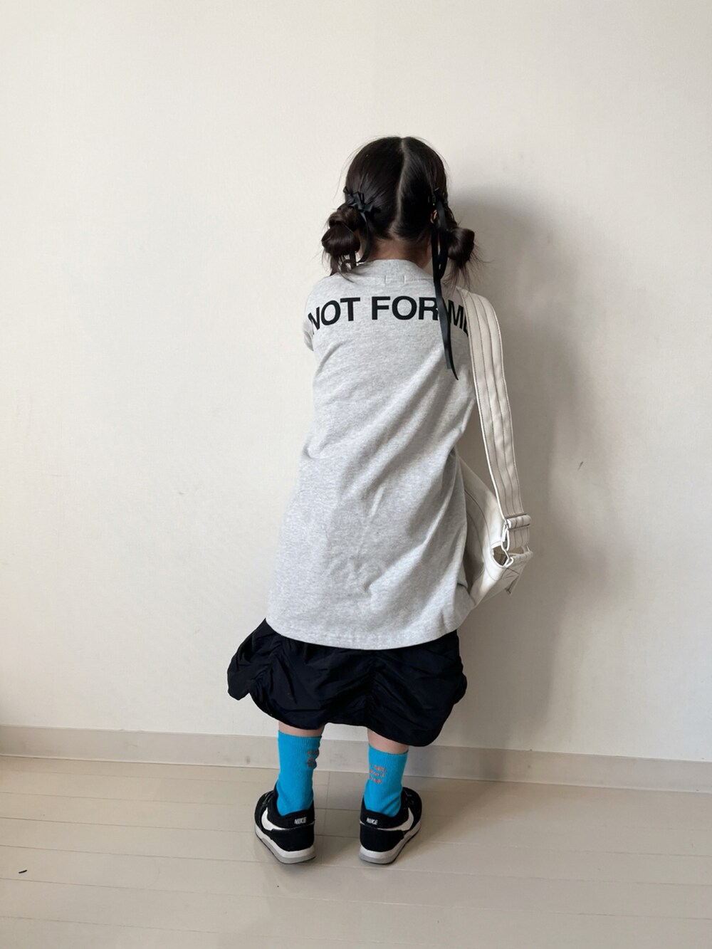 ホワイト系のワンピース、ブラック系のスカート、ブラック系のスニーカーを着用したキッズの冬コーディネートの4枚目の写真