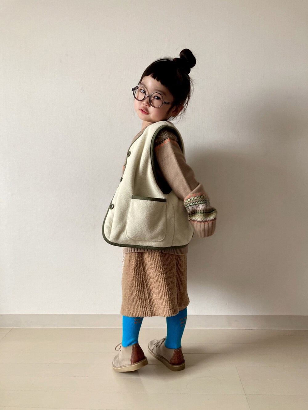 ベージュ系のニット/セーター、グリーン系のベスト、ベージュ系のTシャツ/カットソーを着用したキッズの冬コーディネートの4枚目の写真