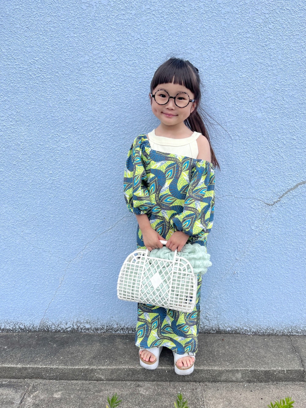 イエロー系のワンピース、ホワイト系のタンクトップ、グリーン系のカーディガン/ボレロを着用したキッズの春コーディネートの3枚目の写真