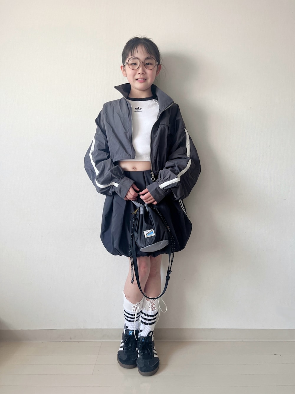 ブラック系のスカート、ブラック系のスニーカー、ブラック系のショルダーバッグを着用したキッズの春コーディネートの3枚目の写真