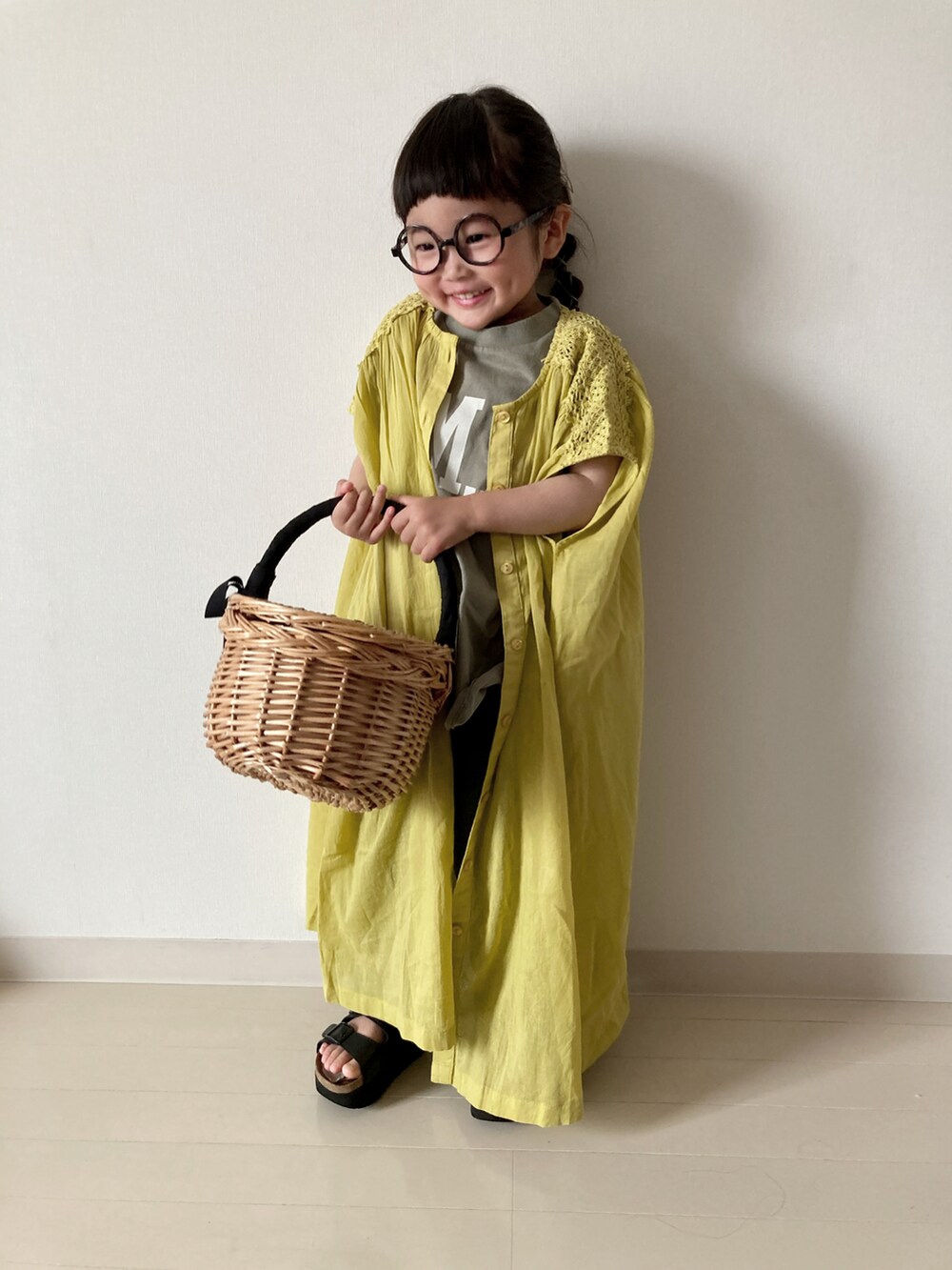 イエロー系のワンピース、グリーン系のTシャツ/カットソー、レッド系のかごバッグを着用したキッズの春コーディネートの3枚目の写真