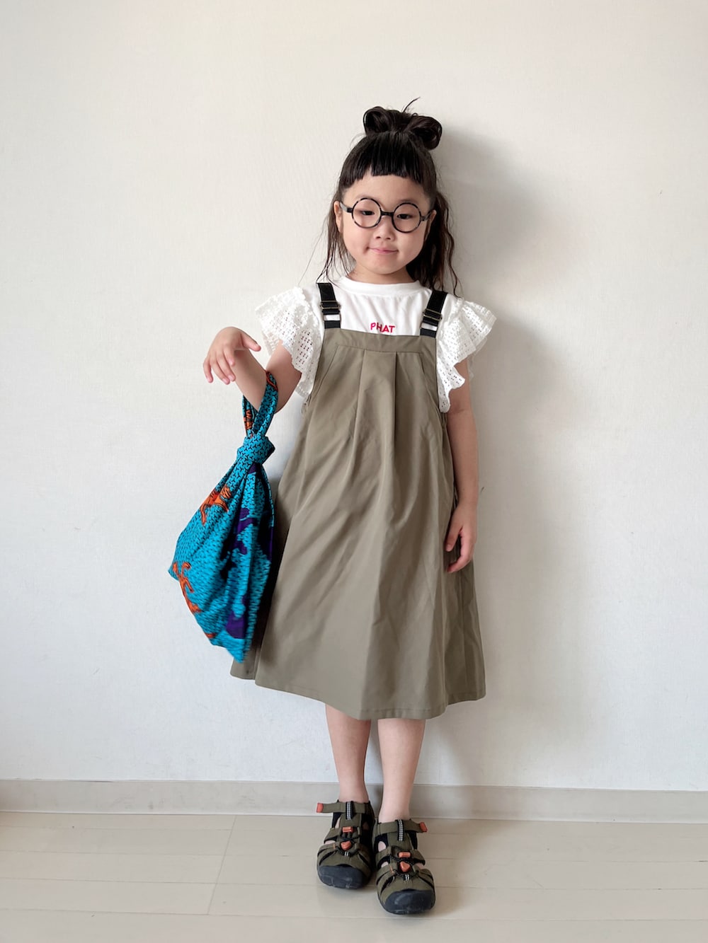 グリーン系のワンピース、ブルー系のハンドバッグ、グリーン系のサンダルを着用したキッズの夏コーディネートの2枚目の写真