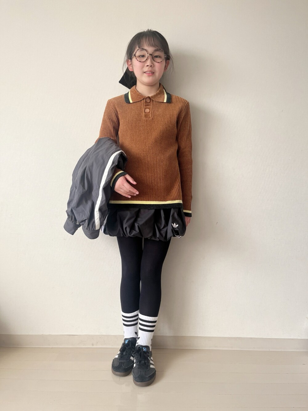 ブラック系のスカート、ブラウン系のニット/セーター、ブラック系のスニーカーを着用したキッズの冬コーディネートの5枚目の写真