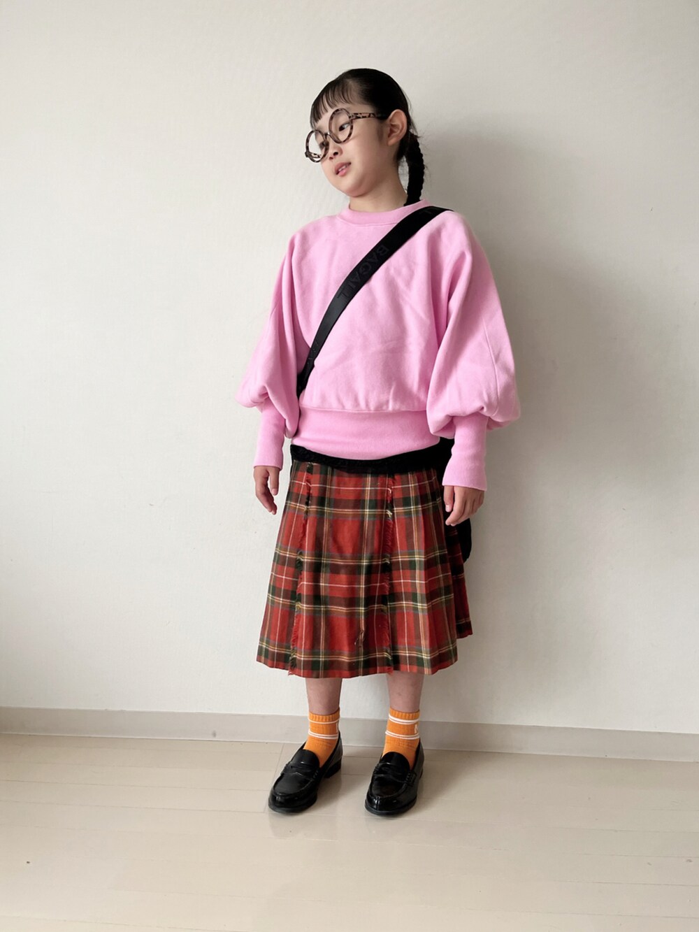 ピンク系のニット/セーター、グリーン系のダウンベスト、ブラック系のローファーを着用したキッズの秋コーディネートの5枚目の写真