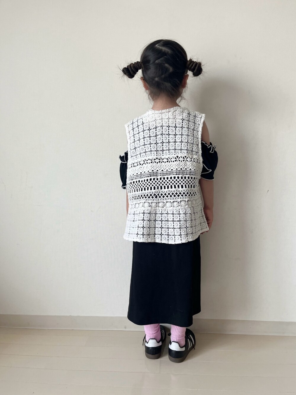 ブラック系のワンピース、ホワイト系のベスト、ホワイト系のハンドバッグを着用したキッズの春コーディネートの5枚目の写真