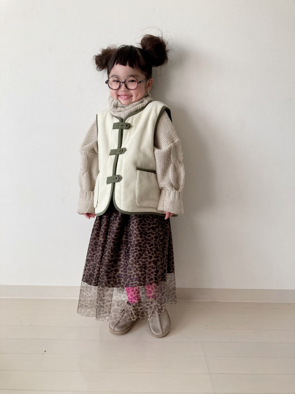 ブラウン系のスカート、グリーン系のベスト、ベージュ系のニット/セーターを着用したキッズの秋コーディネートの4枚目の写真