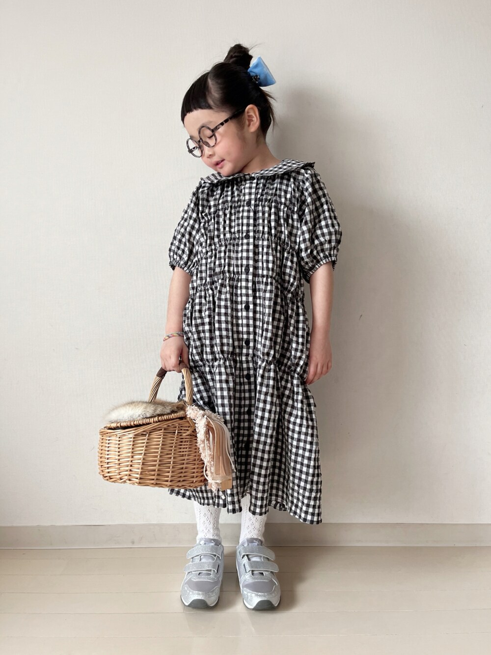 ブラック系のワンピース、ブラック系のカーディガン/ボレロ、ホワイト系のスニーカーを着用したキッズの冬コーディネートの4枚目の写真