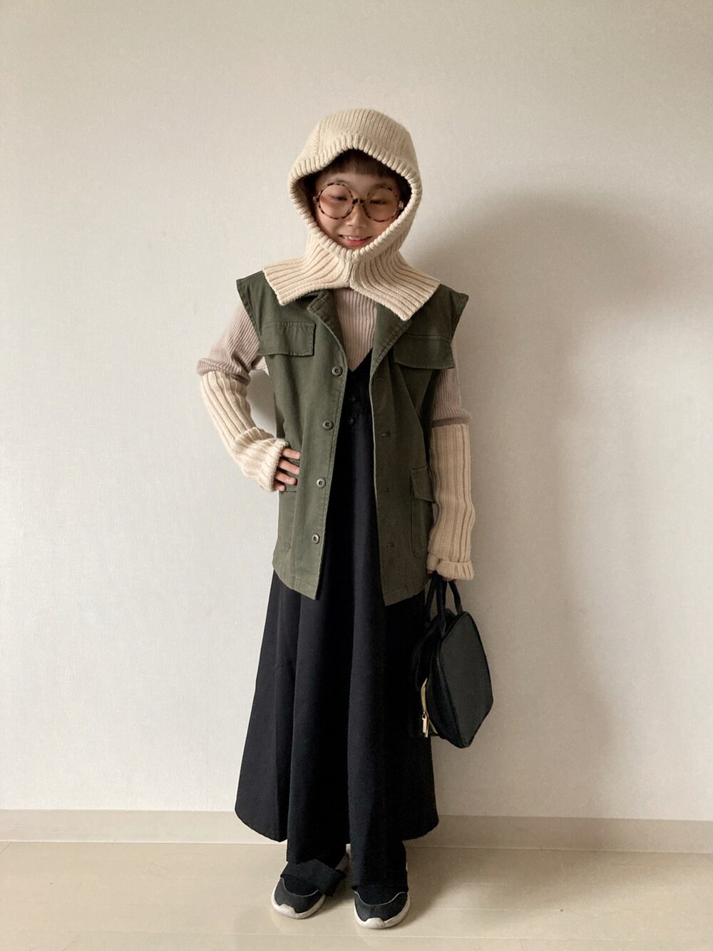 ブラック系のジャンパースカート、ベージュ系のニット/セーター、ブラック系のスニーカーを着用したキッズの秋コーディネートの3枚目の写真