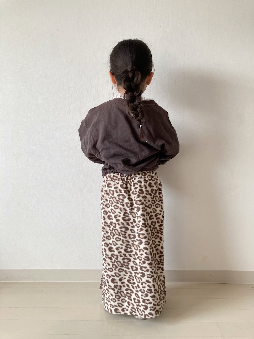 ベージュ系のカーディガン/ボレロ、ベージュ系のTシャツ/カットソー、ブラック系のスニーカーを着用したキッズの冬コーディネートの5枚目の写真