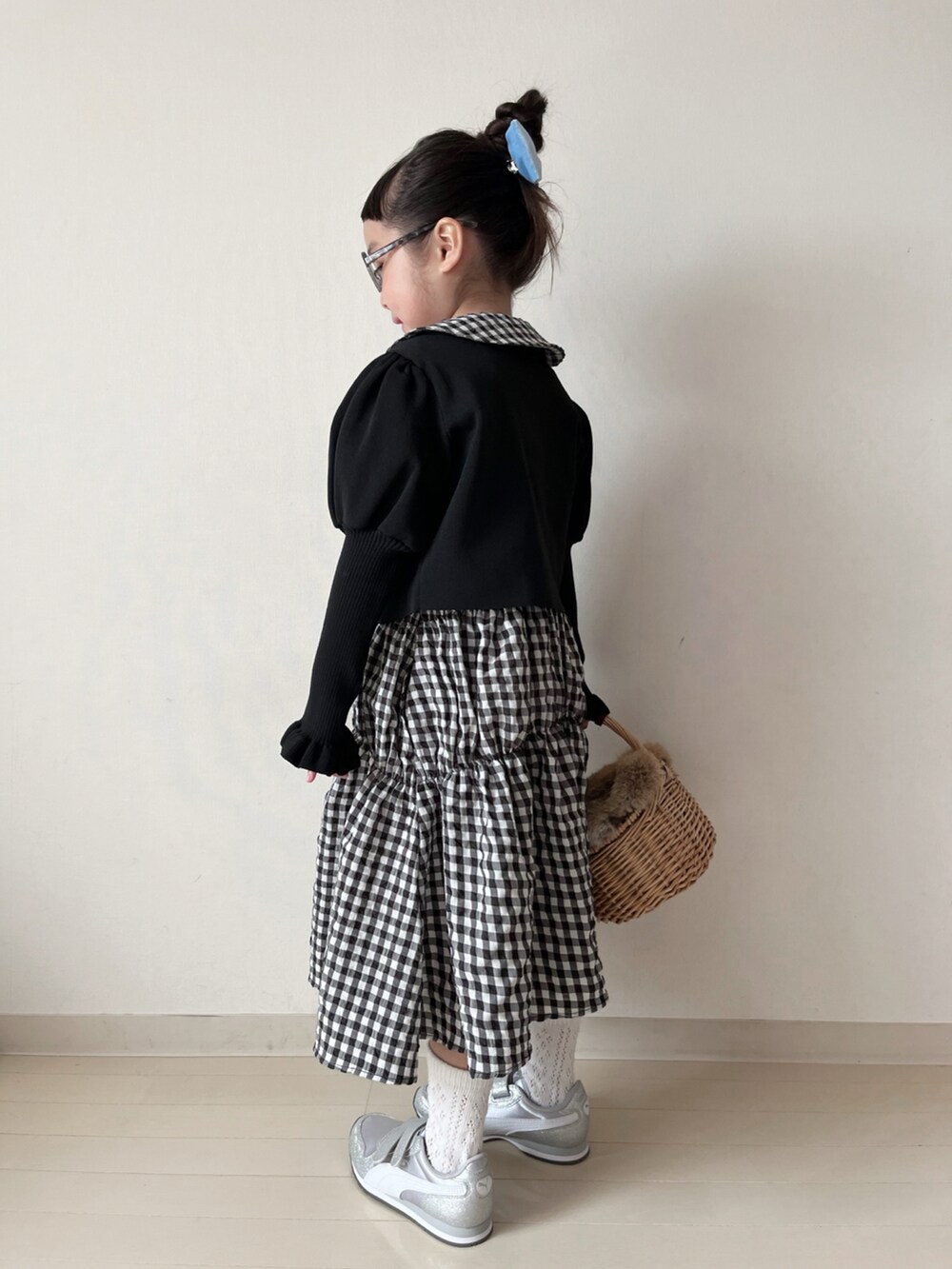 ブラック系のワンピース、ブラック系のカーディガン/ボレロ、ホワイト系のスニーカーを着用したキッズの冬コーディネートの3枚目の写真