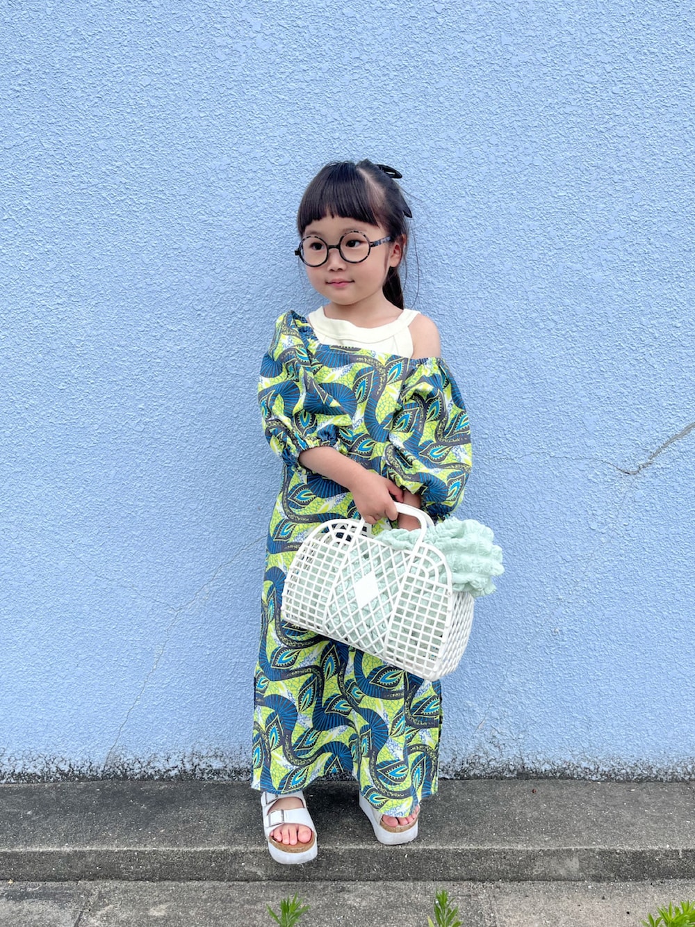 イエロー系のワンピース、ホワイト系のタンクトップ、グリーン系のカーディガン/ボレロを着用したキッズの春コーディネートの2枚目の写真