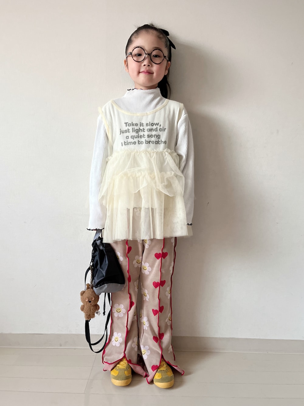 イエロー系のTシャツ/カットソー、ホワイト系のパンツ、ブラック系のショルダーバッグを着用したキッズの冬コーディネートの2枚目の写真