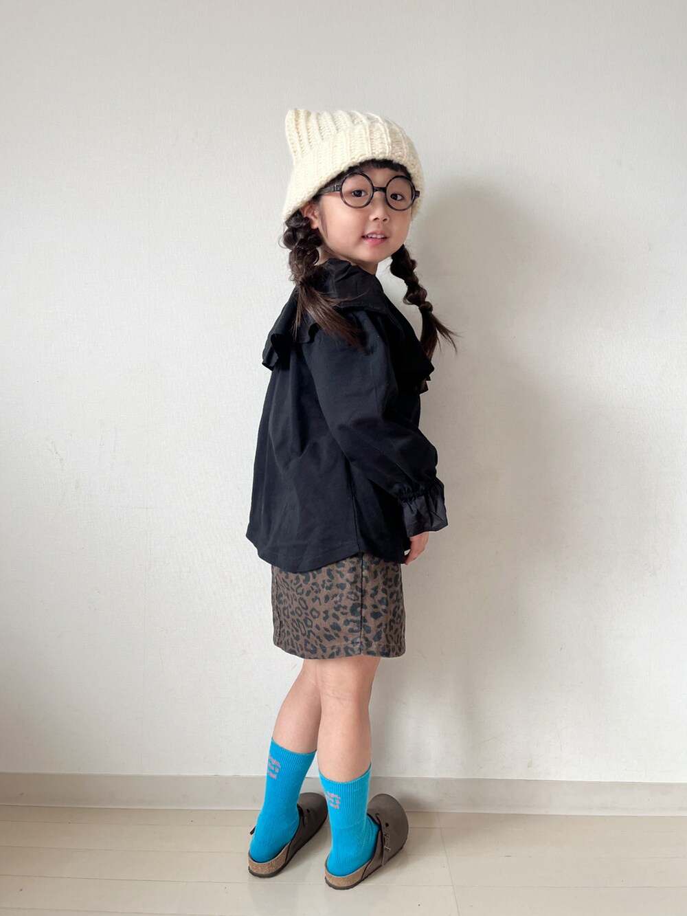 ブラック系のTシャツ/カットソー、ベージュ系のスカート、ブラウン系のサンダルを着用したキッズの秋コーディネートの4枚目の写真