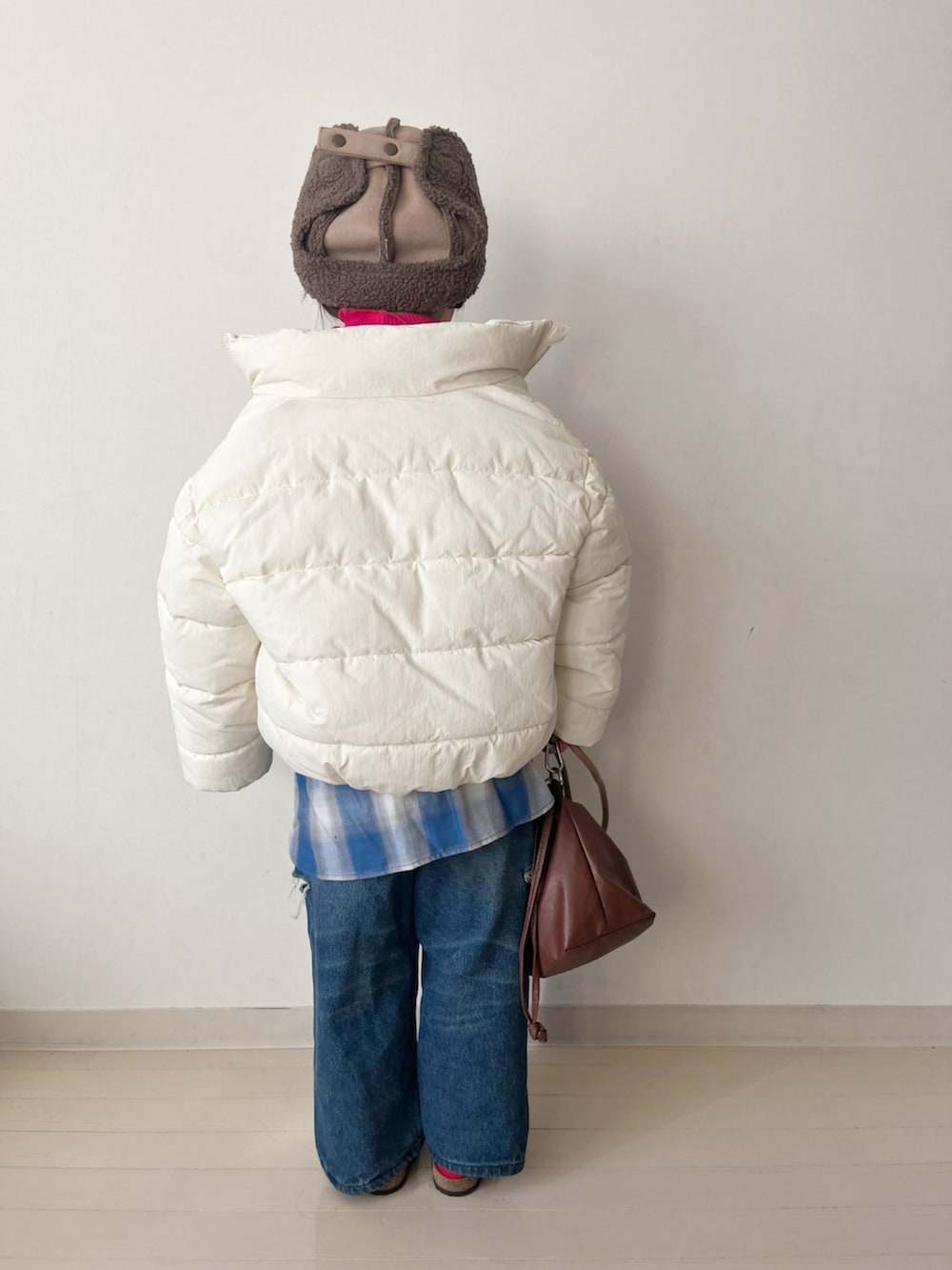 ホワイト系のダウンジャケット/コート、レッド系のTシャツ/カットソー、ブルー系のデニムパンツを着用したキッズの冬コーディネートの4枚目の写真