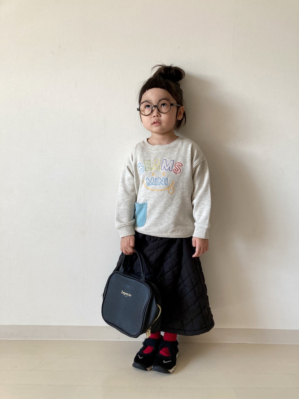 ホワイト系のスウェット、ブラック系のワンピース、ブラック系のスニーカーを着用したキッズの秋コーディネートの2枚目の写真