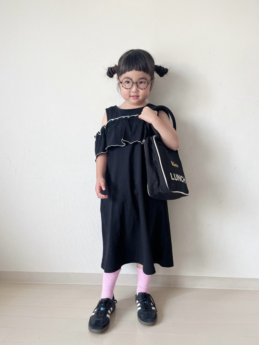 ブラック系のワンピース、ホワイト系のベスト、ホワイト系のハンドバッグを着用したキッズの春コーディネートの2枚目の写真