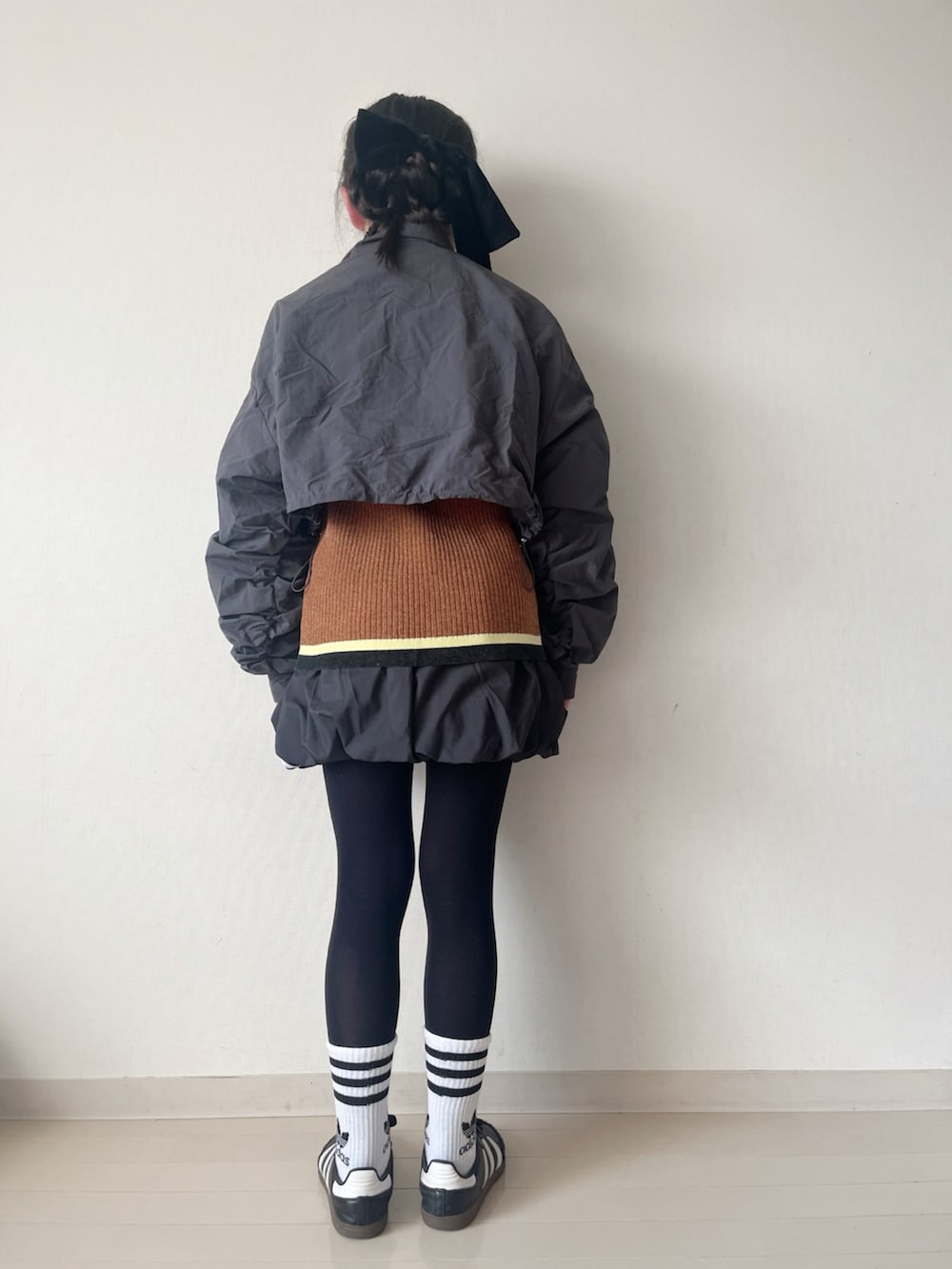 ブラック系のスカート、ブラウン系のニット/セーター、ブラック系のスニーカーを着用したキッズの冬コーディネートの3枚目の写真