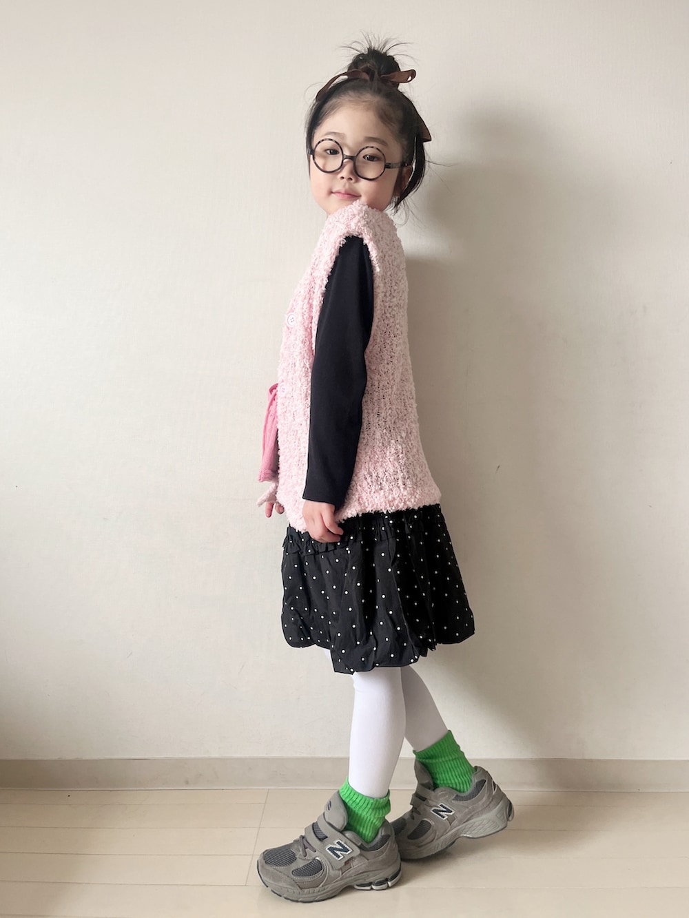 ピンク系のニット/セーター、ブラック系のスカート、グレー系のスニーカーを着用したキッズの冬コーディネートの2枚目の写真