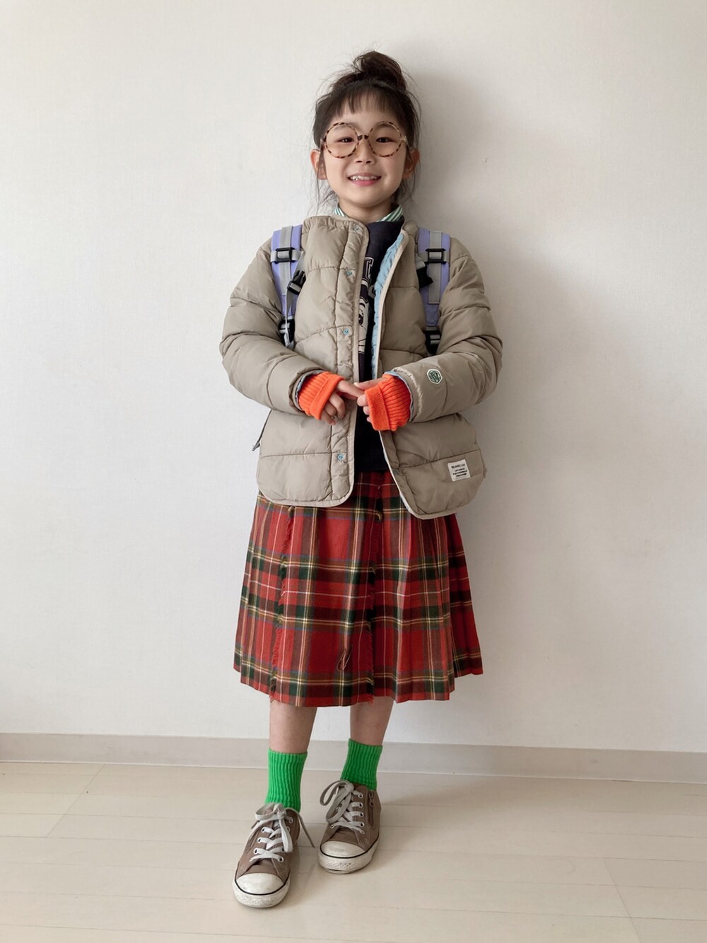 ブラウン系のブルゾン、グレー系のスウェット、レッド系のスカートを着用したキッズの秋コーディネートの2枚目の写真