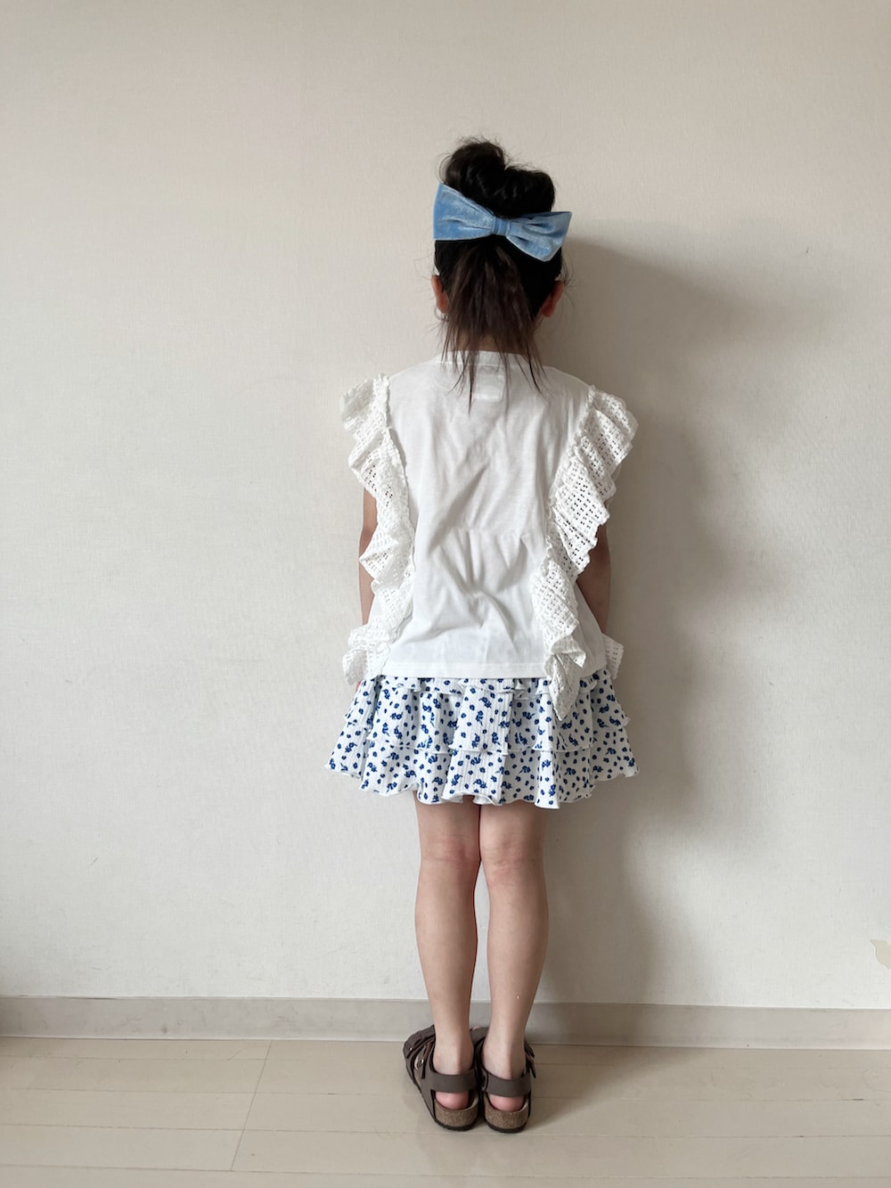 ホワイト系のスカート、ブラウン系のサンダル、ホワイト系のTシャツ/カットソーを着用したキッズの夏コーディネートの4枚目の写真
