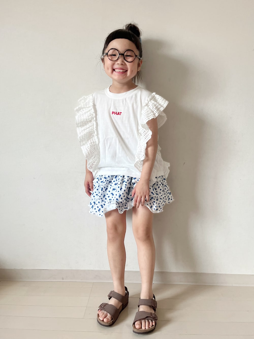ホワイト系のスカート、ブラウン系のサンダル、ホワイト系のTシャツ/カットソーを着用したキッズの夏コーディネートの3枚目の写真