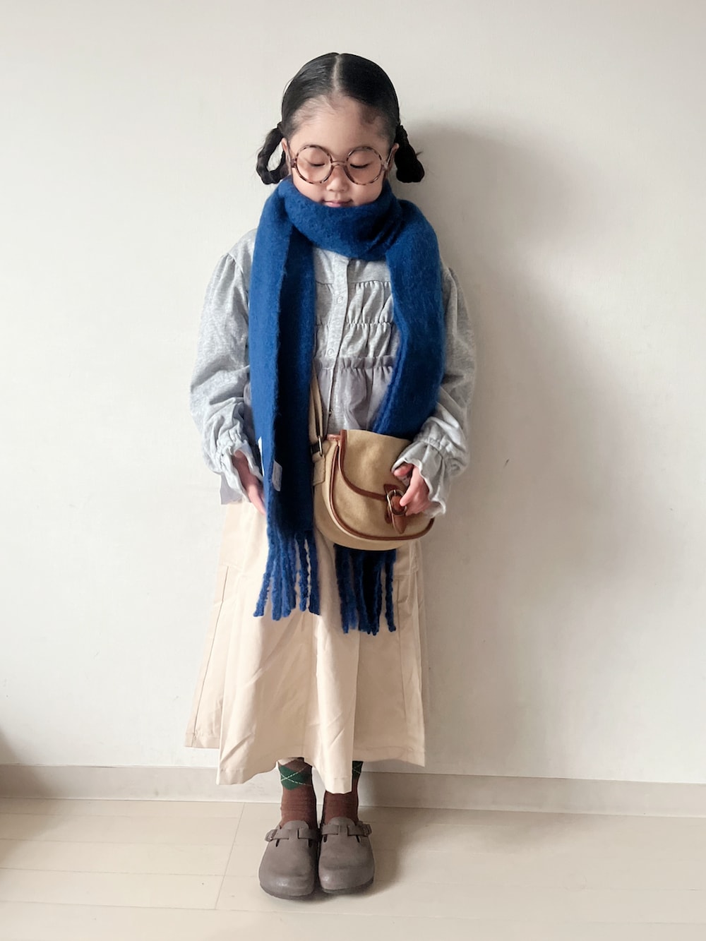 グレー系のカーディガン/ボレロ、ベージュ系のショルダーバッグ、ベージュ系のスカートを着用したキッズの秋コーディネートの2枚目の写真