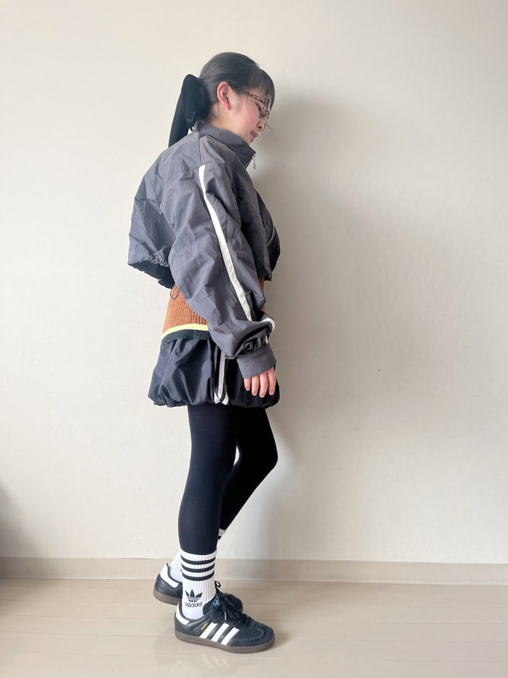 ブラック系のスカート、ブラウン系のニット/セーター、ブラック系のスニーカーを着用したキッズの冬コーディネートの2枚目の写真