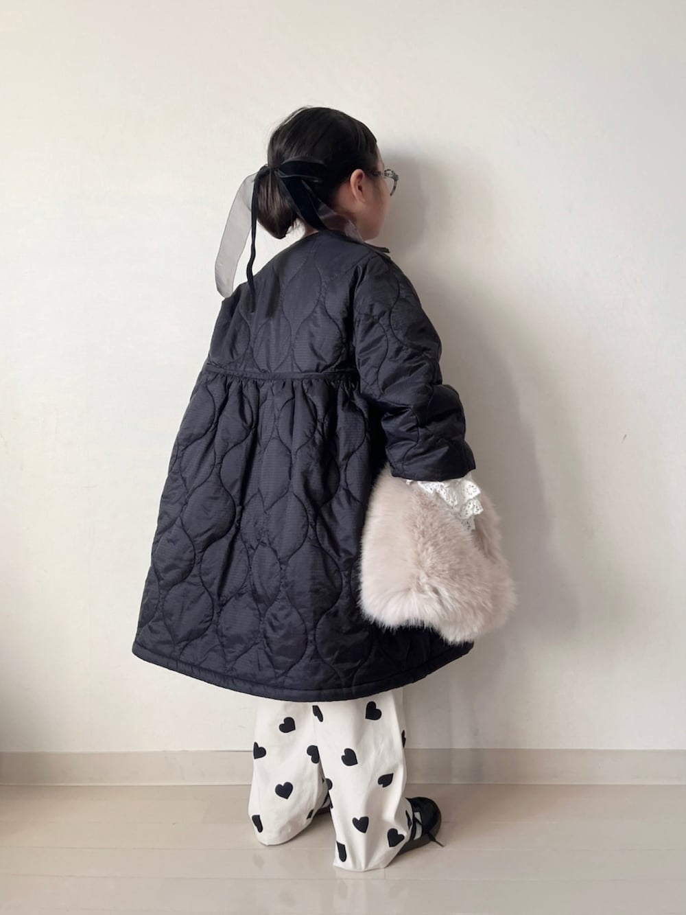 ブラック系のミリタリージャケット、ブラック系のニット/セーター、ホワイト系のTシャツ/カットソーを着用したキッズの秋コーディネートの2枚目の写真