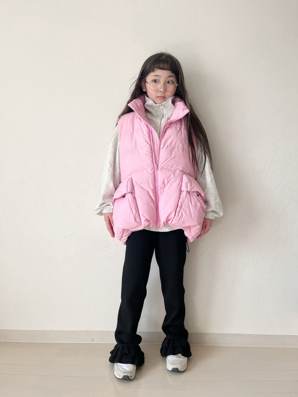 ブラック系のその他パンツ、ピンク系のダウンベスト、ベージュ系のスウェットを着用したキッズの冬コーディネートの3枚目の写真