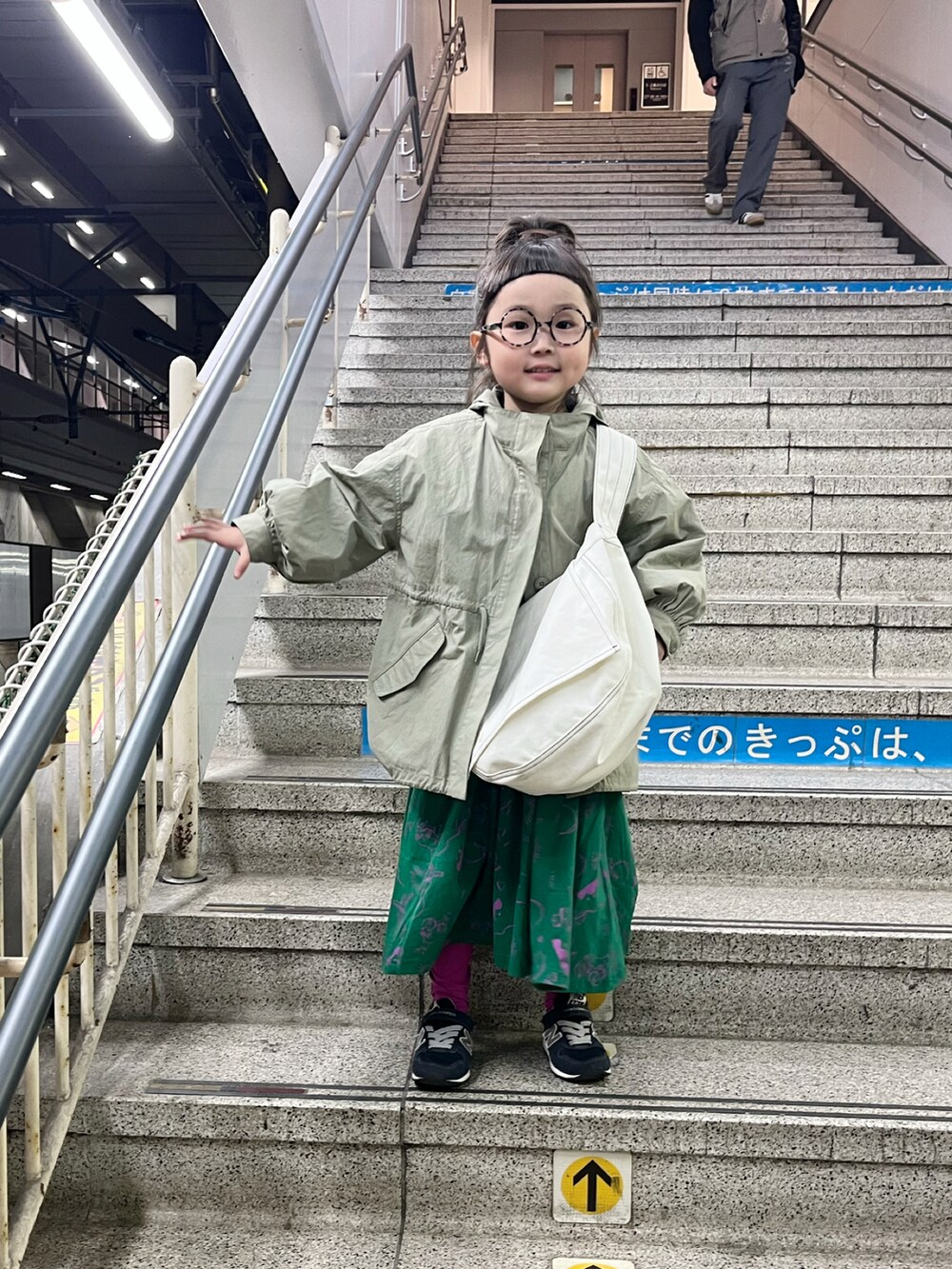 グリーン系のワンピース、ホワイト系のショルダーバッグ、グリーン系のステンカラーコートを着用したキッズの春コーディネートの5枚目の写真