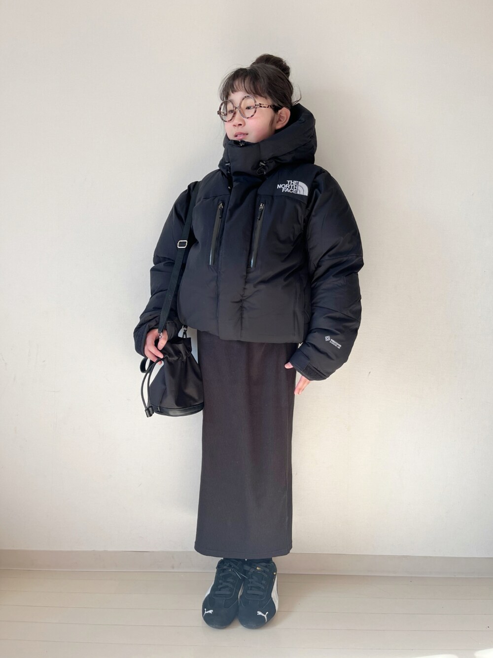 ブラック系のダウンジャケット/コート、ブラック系のスカート、ベージュ系のニット/セーターを着用したキッズの冬コーディネートの4枚目の写真