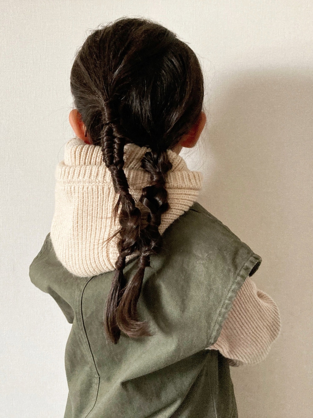 ブラック系のジャンパースカート、ベージュ系のニット/セーター、ブラック系のスニーカーを着用したキッズの秋コーディネートの5枚目の写真