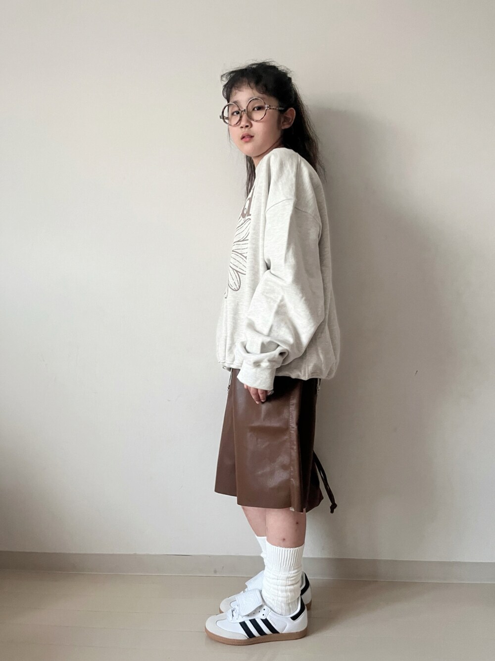 ベージュ系のスウェット、グリーン系のTシャツ/カットソー、ブラウン系のショルダーバッグを着用したキッズの秋コーディネートの2枚目の写真