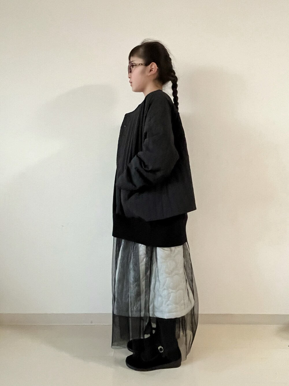 ブラック系のナイロンジャケット、ブラック系のニット/セーター、ホワイト系のスカートを着用したキッズの冬コーディネートの4枚目の写真