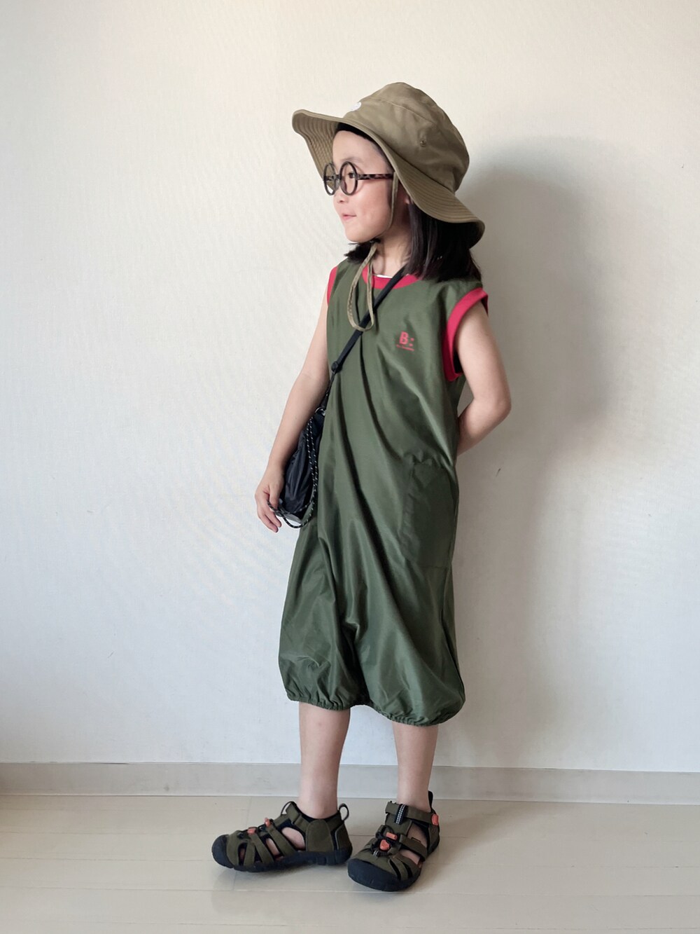 グリーン系のワンピース、ブラック系のショルダーバッグ、グリーン系のサンダルを着用したキッズの夏コーディネートの4枚目の写真