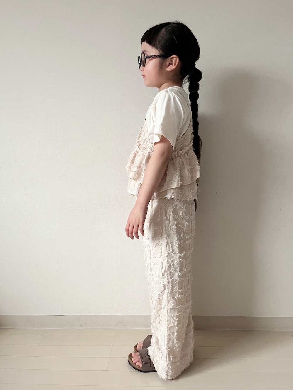 ベージュ系のショルダーバッグ、ブラウン系のサンダル、ベージュ系のTシャツ/カットソーを着用したキッズの春コーディネートの4枚目の写真