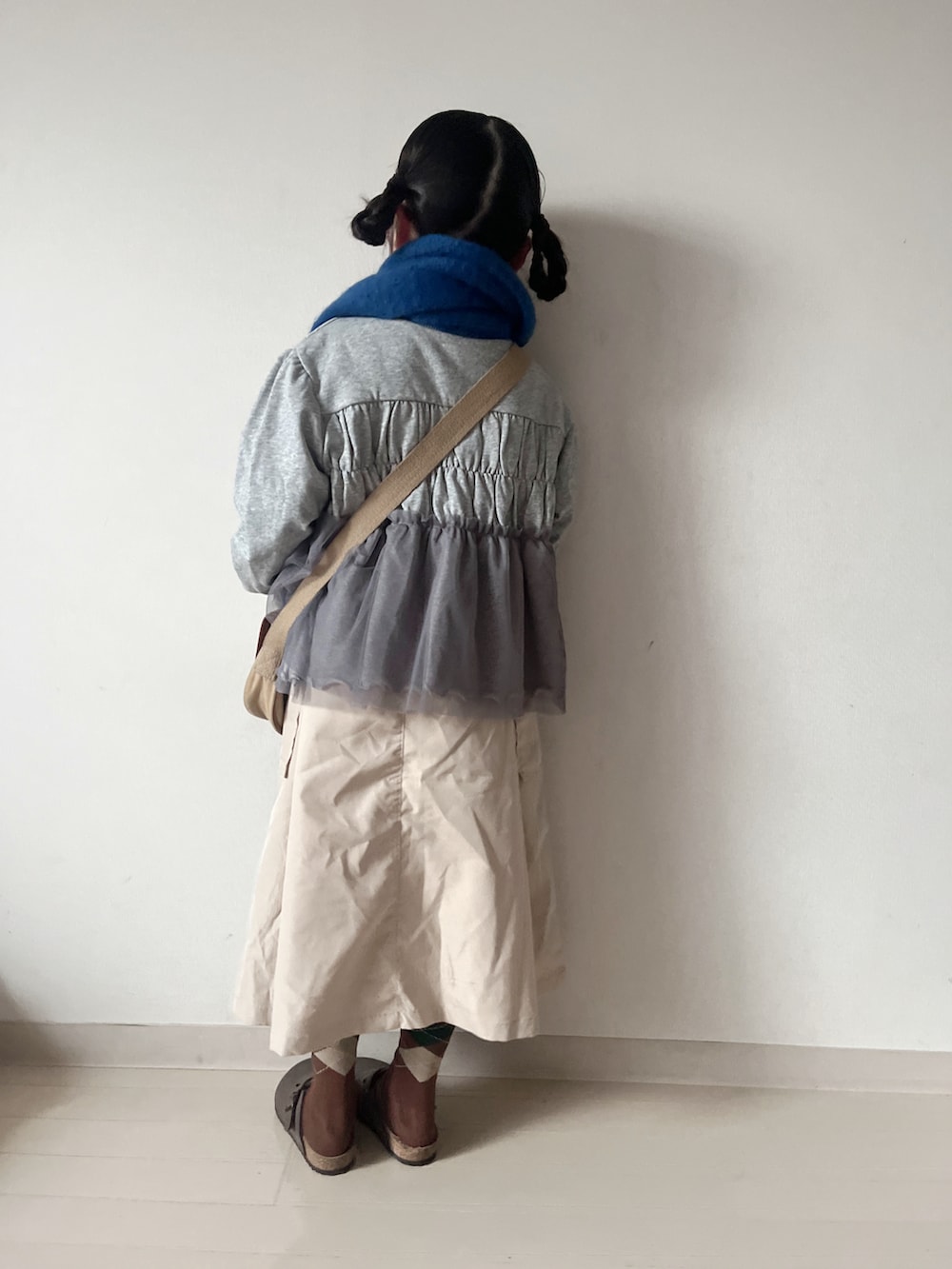 グレー系のカーディガン/ボレロ、ベージュ系のショルダーバッグ、ベージュ系のスカートを着用したキッズの秋コーディネートの5枚目の写真