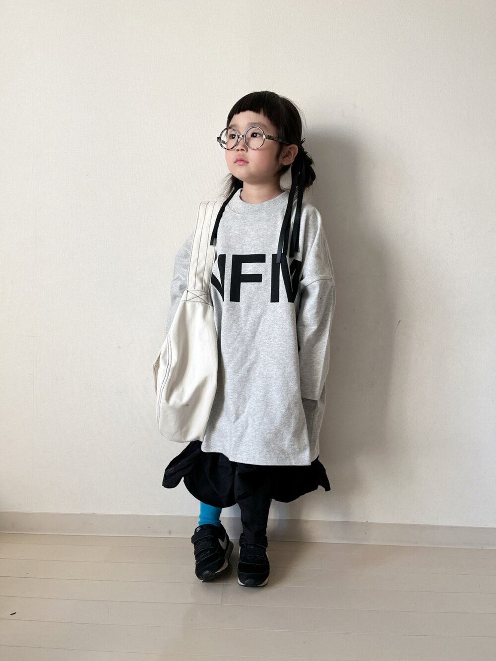 ホワイト系のワンピース、ブラック系のスカート、ブラック系のスニーカーを着用したキッズの冬コーディネートの2枚目の写真