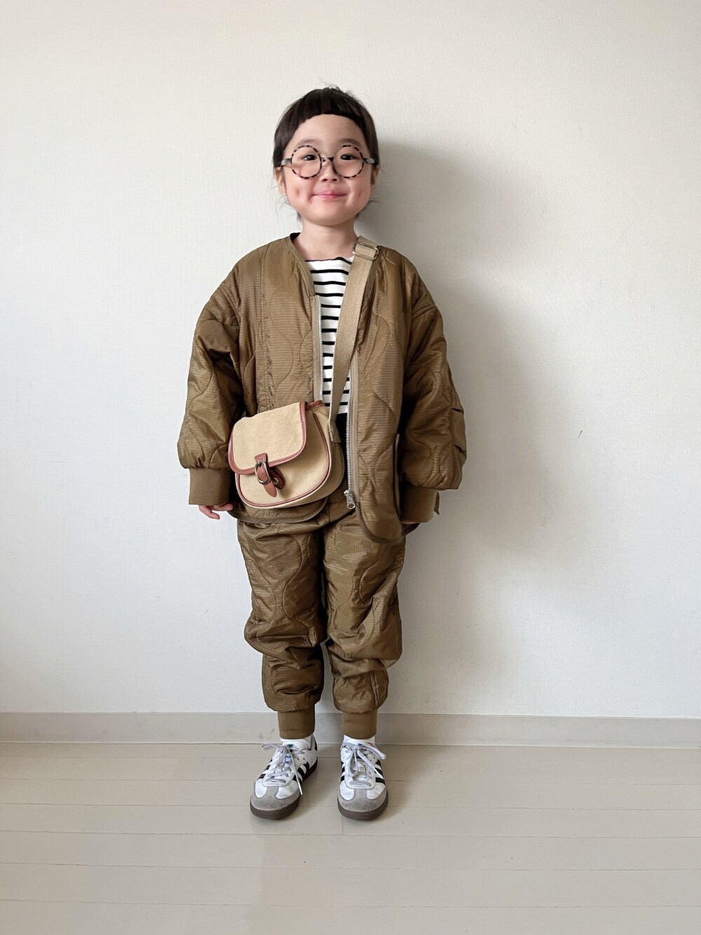 ブラウン系のダウンジャケット/コート、ブラウン系のその他パンツ、ブラック系のTシャツ/カットソーを着用したキッズの秋コーディネートの4枚目の写真