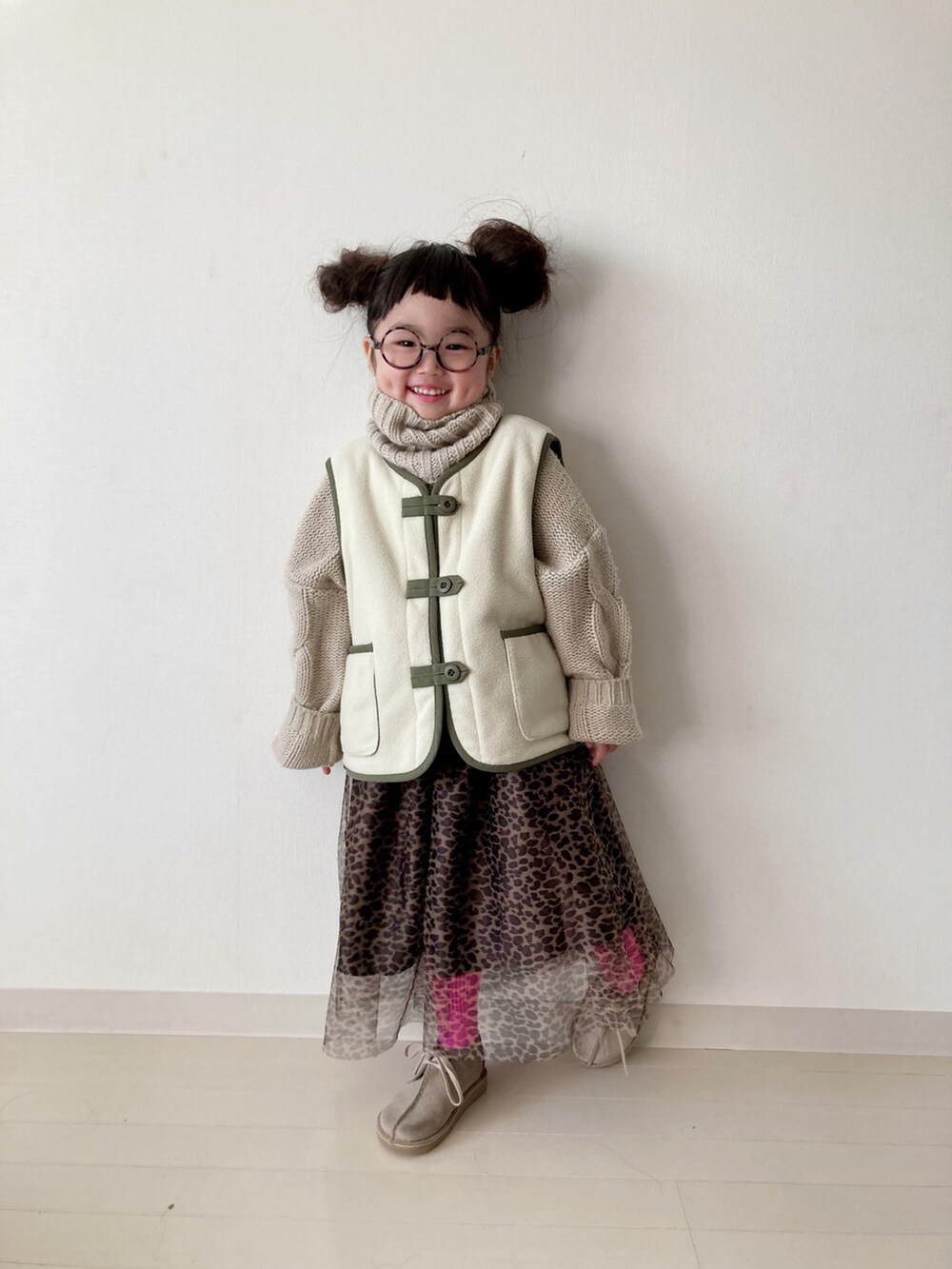 ブラウン系のスカート、グリーン系のベスト、ベージュ系のニット/セーターを着用したキッズの秋コーディネートの3枚目の写真