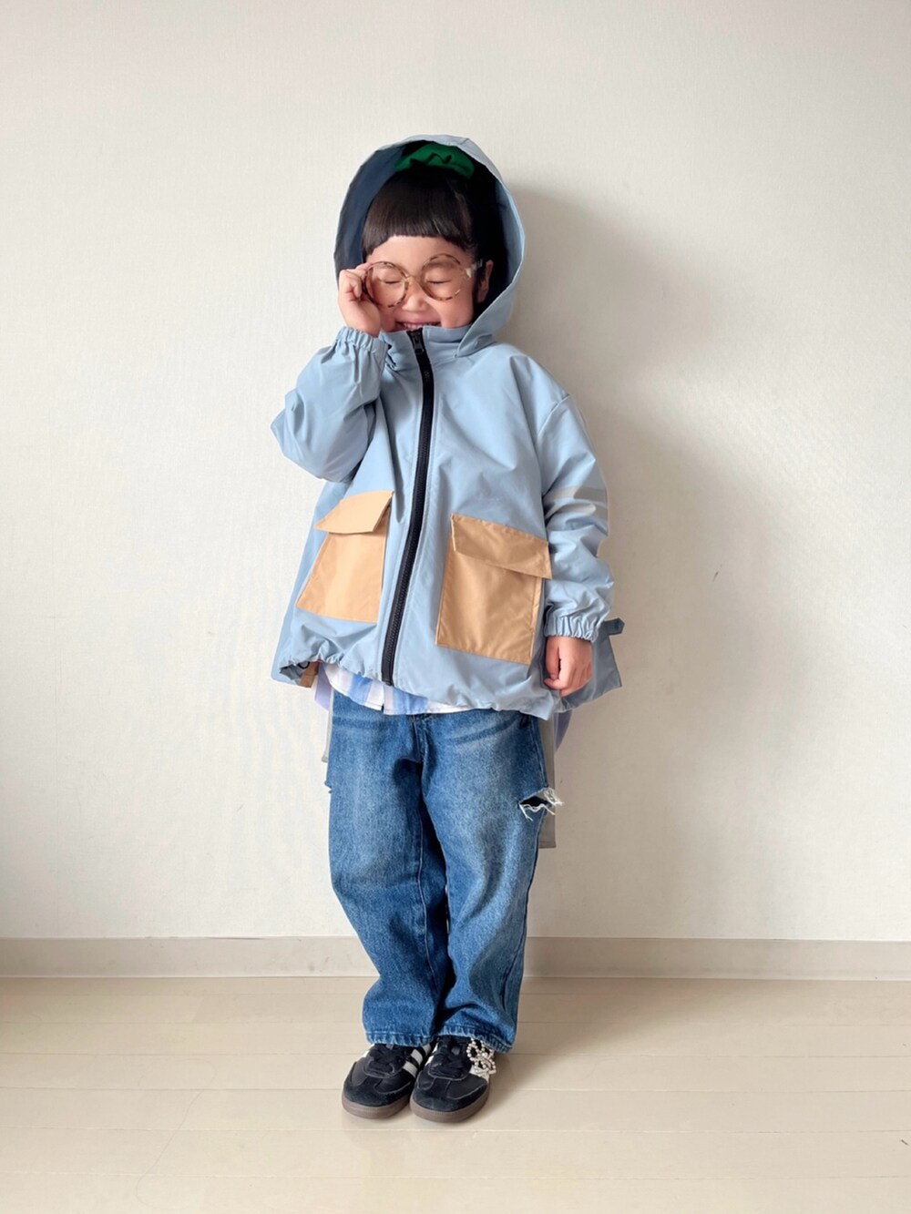 ブルー系のナイロンジャケット、オレンジ系のニット/セーター、ブルー系のデニムパンツを着用したキッズの秋コーディネートの3枚目の写真